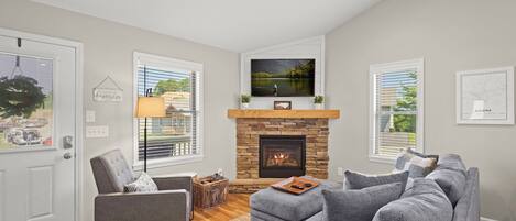 Cozy up: Plush sofa, chic chair, TV, deck views, and a crackling indoor fireplace.