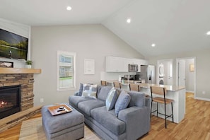 Inviting living space: Sink into a comfy sofa, enjoy the chic chair, catch a show on TV, step onto the deck, and bask in the glow of the indoor fireplace.