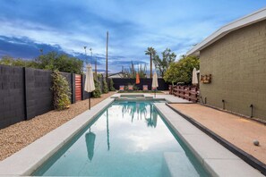Private backyard with heated pool (by request), spa, bocce ball, and outdoor seating/loungers.