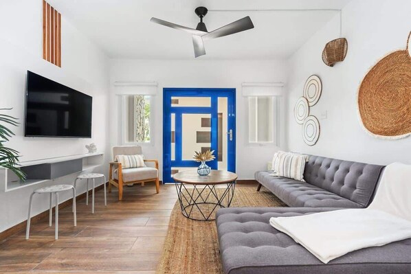 The living room has a sectional sofa, flat screen smart TV and arm chair
