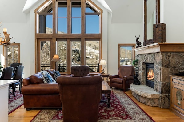 Cozy Up by the Fire in this Gorgeous Two Story Living Room with Sweeping Mountain Views.