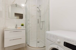Bright bathroom with washing machine and shower cabin. 