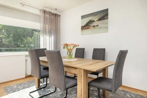 Cozy dining corner with a wooden table and upholstered chairs, set against a simple yet inviting interior.

