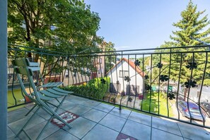 Charming balcony furnished with a small table and chairs, surrounded by lush greenery - ideal for morning coffee or afternoon relaxation.

