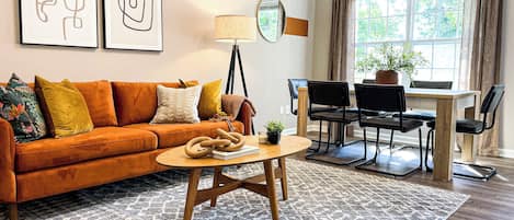 Living room with cozy couch and dining area beside huge window