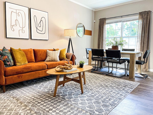 Living room with cozy couch and dining area beside huge window