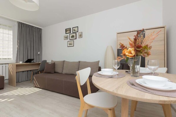 Living room with a sofa bed, TV, desk with chair and dining area.