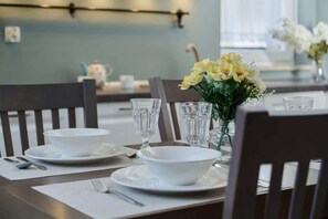 Dining table set for four, with stylish tableware and fresh flowers, creating a welcoming dining experience.

