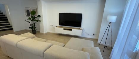 Living room with large sofa and 70 inch TV with PrimeVideo and Airplay TV