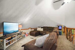 Upper level loft area with cozy cough, flat screen smart TV, arcade machine