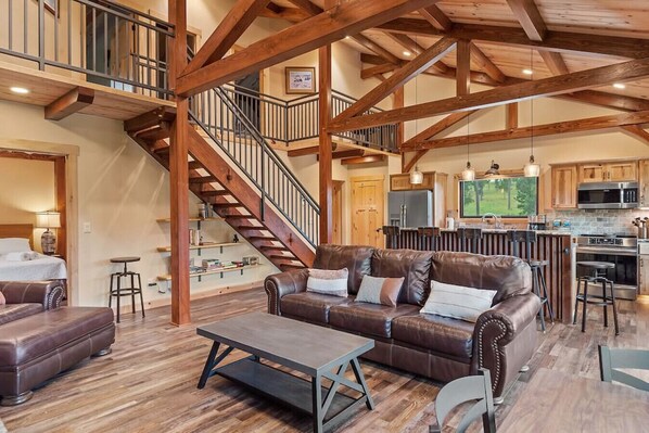 Inviting cabin which offers a perfect blend of rustic charm and contemporary comfort with couches, stools, kitchen countertops, and a well-stocked kitchen