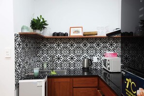 Equipped kitchen with a toaster, a microwave, a kettle, untensil, pots, plates..