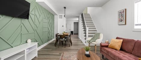 A captivating view of our inviting living area, featuring a glimpse of the elegant staircase and a welcoming dining table, creating a harmonious and stylish living space.