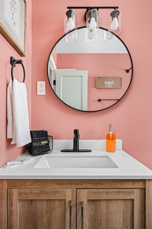 Step into a beautifully designed space featuring a sleek mirror, plush towels, luxurious hand soap, and an elegant sink that adds a touch of sophistication to your daily routine. 