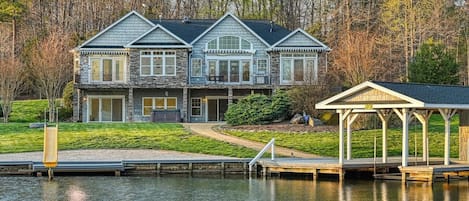 Photo from across the lagoon looking up at the house, slide and boathouse/dock