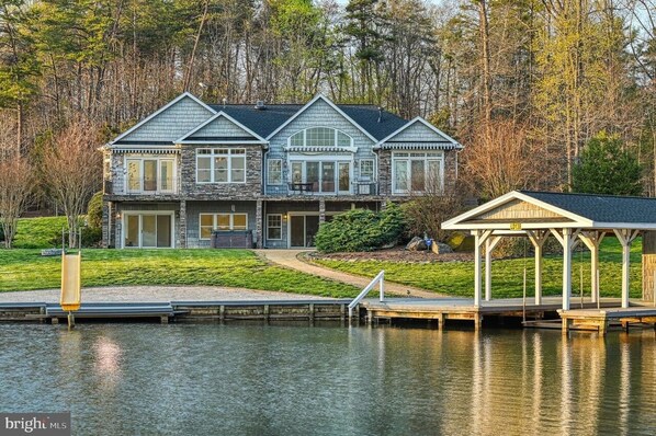 Photo from across the lagoon looking up at the house, slide and boathouse/dock