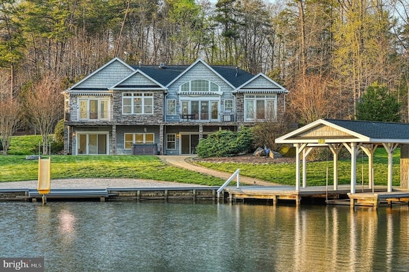 Photo from across the lagoon looking up at the house, slide and boathouse/dock