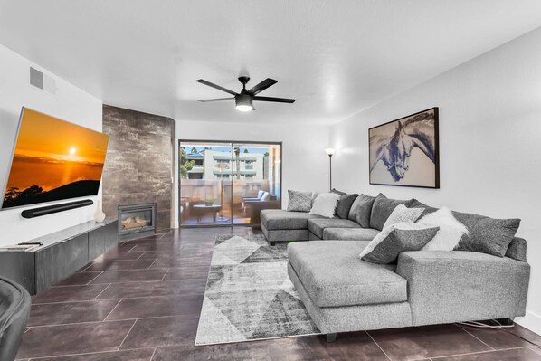 Living room has 65" Smart TV with Cable, sectional sofa & fireplace