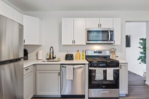 Fully equipped kitchen with stainless steel appliances, microwave, gas stove