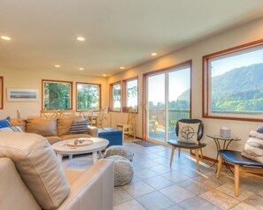 Living room with TV, wood fireplace and access to deck with mountain view.