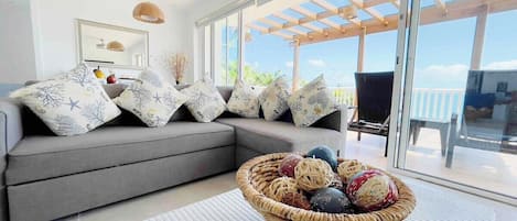 Relax in the beachfront villa's living room, featuring a queen-size sofa bed and mesmerizing ocean views. Embrace the soothing sounds of the waves and unwind in comfort while enjoying the scenic beauty of the coastal surroundings. 