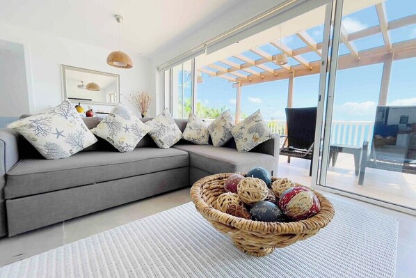 Relax in the beachfront villa's living room, featuring a queen-size sofa bed and mesmerizing ocean views. Embrace the soothing sounds of the waves and unwind in comfort while enjoying the scenic beauty of the coastal surroundings. 