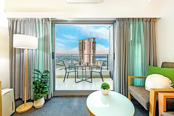 Sliding doors open up to reveal a private balcony, set with a two-seater table overlooking the CBD skyline and ocean.