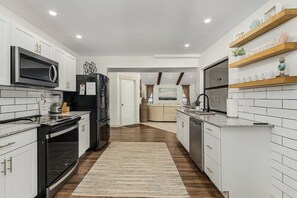 Electric stove and fully stocked kitchen for cooking meals. 