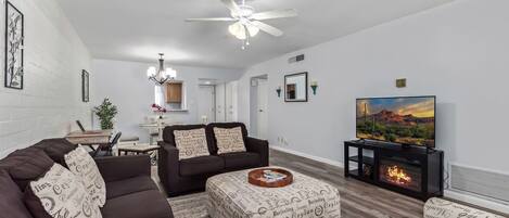 Cozy & Inviting living space featuring a Smart TV, electric fireplace, designer furnishings, a workstation, covered balcony, and a dining room table to accommodate up to 4 guests.