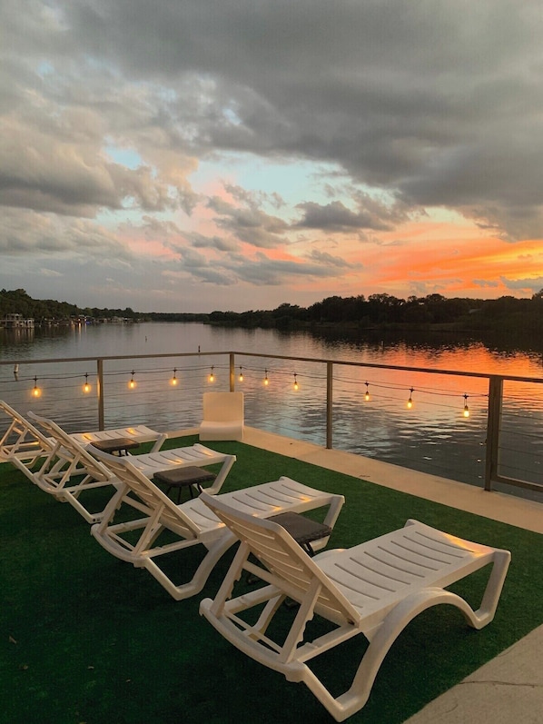 Relax and unwind with breathtaking sunset views over Lake LBJ from the upper deck. The comfortable lounge chairs and string lights create a perfect setting for evening cocktails or simply soaking in the peaceful surroundings of the water and nature.