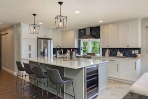 Entertain and dine with ease in this open and spacious kitchen featuring a large island and stylish seating. The design is perfect for social gatherings, offering a seamless flow between the kitchen and dining space, and a fantastic view of the lake.