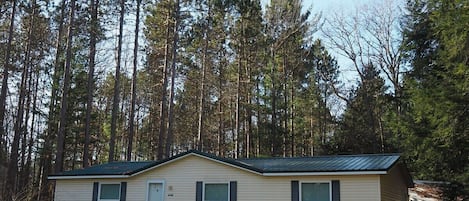 A nice overview of the front of the house, highlighting the front porch and the huge pine, cedar, and hemlock trees in the backyard.