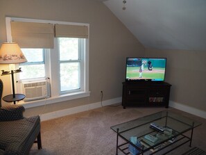 OVERALL:  The home has a comfy living room with a sofa, coffee table, chair, lamp, window A/C, and live streaming television.
