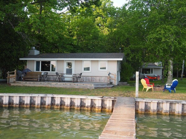 OVERALL:  The front of the cottage on Little Glen Lake, highlighting the lake, lakefront deck, private dock, and the bonfire ring.