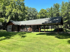 EXTERIOR: Another view of the front of the cabin in summer.
