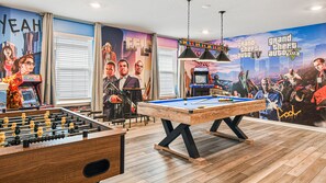 Game room with GTA theme, featuring foosball, pool table, and arcade.