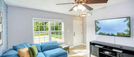 Living room with cozy couch, TV rack, and airy window