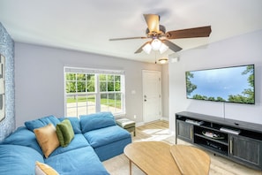 Living room with cozy couch, TV rack, and airy window