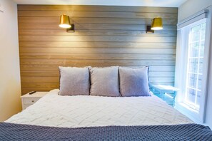 The bedroom has a king bed with night stands and wall sconces.
