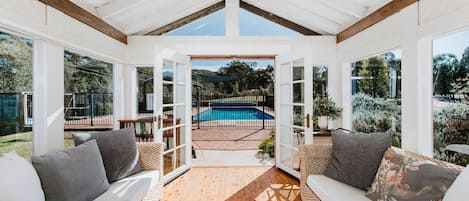 A comfortably furnished sunroom opens up to the pool area through sliding glass doors.