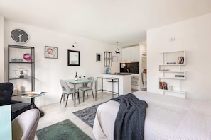 An open-plan layout showcasing a cozy sleeping area, a dining space, and a fully equipped kitchen.

