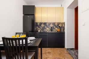 A modern kitchen with sleek cabinetry, floral backsplash, and a spacious dining table for shared meals.
