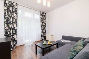A bright living area with a floral accent, comfortable grey sofa, and coffee table for relaxation.
