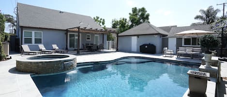 Outdoor dining table, living set and chaise loungers along side beautiful pool.