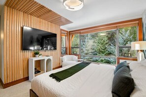 Another angle of the upstairs primary featuring real oak accent wall behind the 65" Smart TV w/ cable. Check out the huge picturesque windows looking out on the secluded tree lined backyard