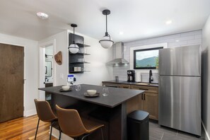 Open-concept kitchen with stainless appliances, standard, drip-style coffee maker, and breakfast bar seating for 2.