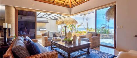 The living room with a view of the pool and the ocean