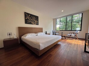 La habitación principal te ofrece un espacio armonioso con una vista a la naturaleza, una cama king y un área para sentarse.