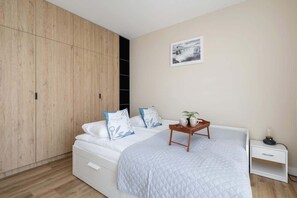 A stylish bedroom featuring a comfortable bed, wooden wardrobe, and soft neutral tones.