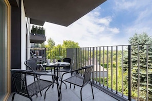 A balcony with a table and chairs, offering a serene view of the surrounding greenery.